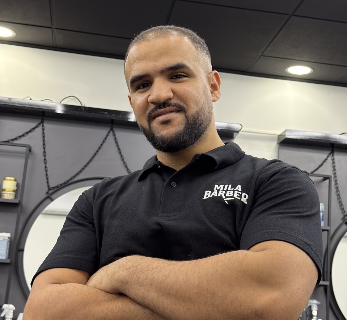 Mohammed, con los brazos cruzados delante de los espejos de la barbería